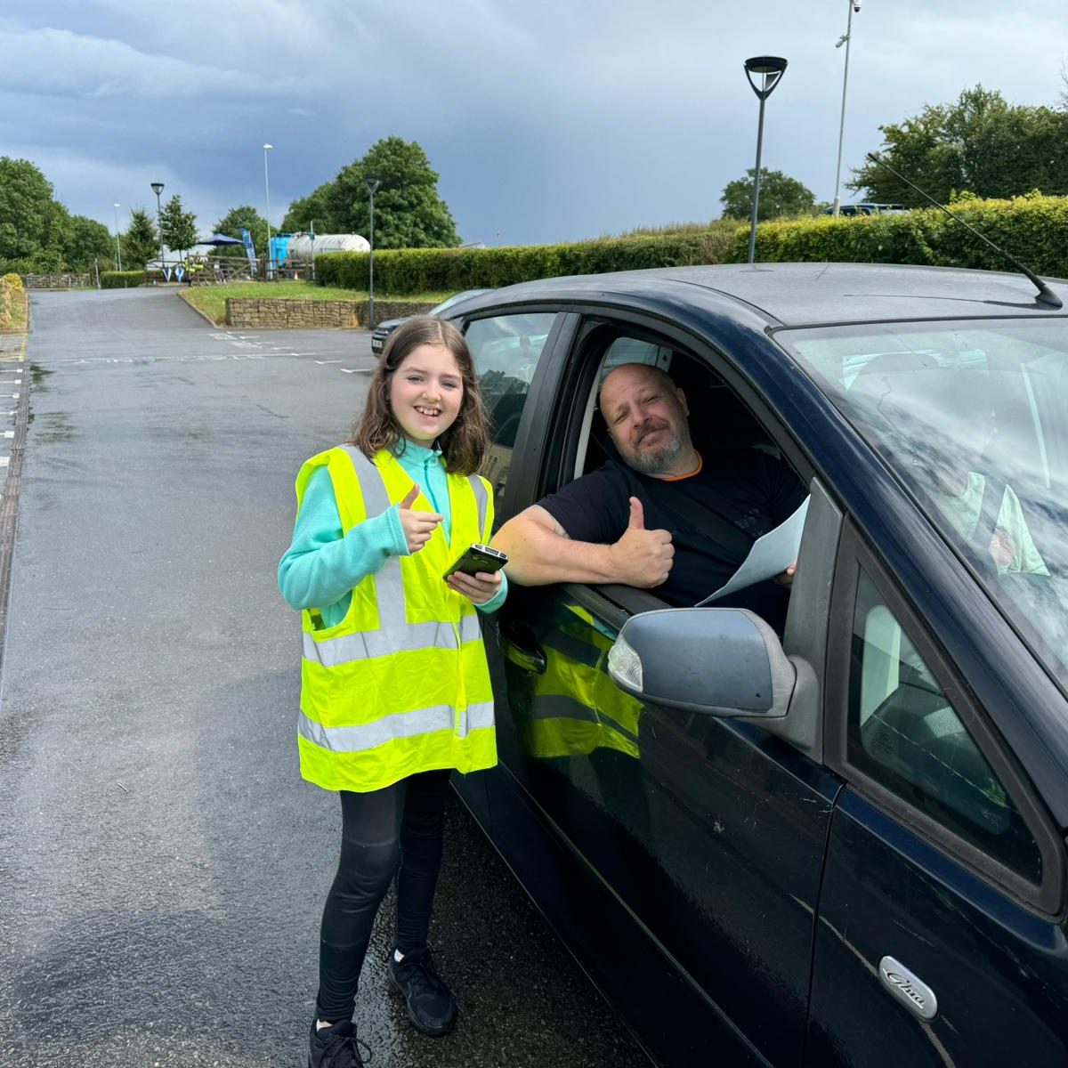 Child volunteer and customer posing for camera with thumbs up.