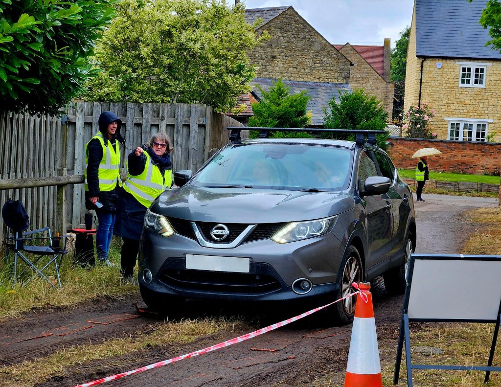 Two volunteers directing car.
